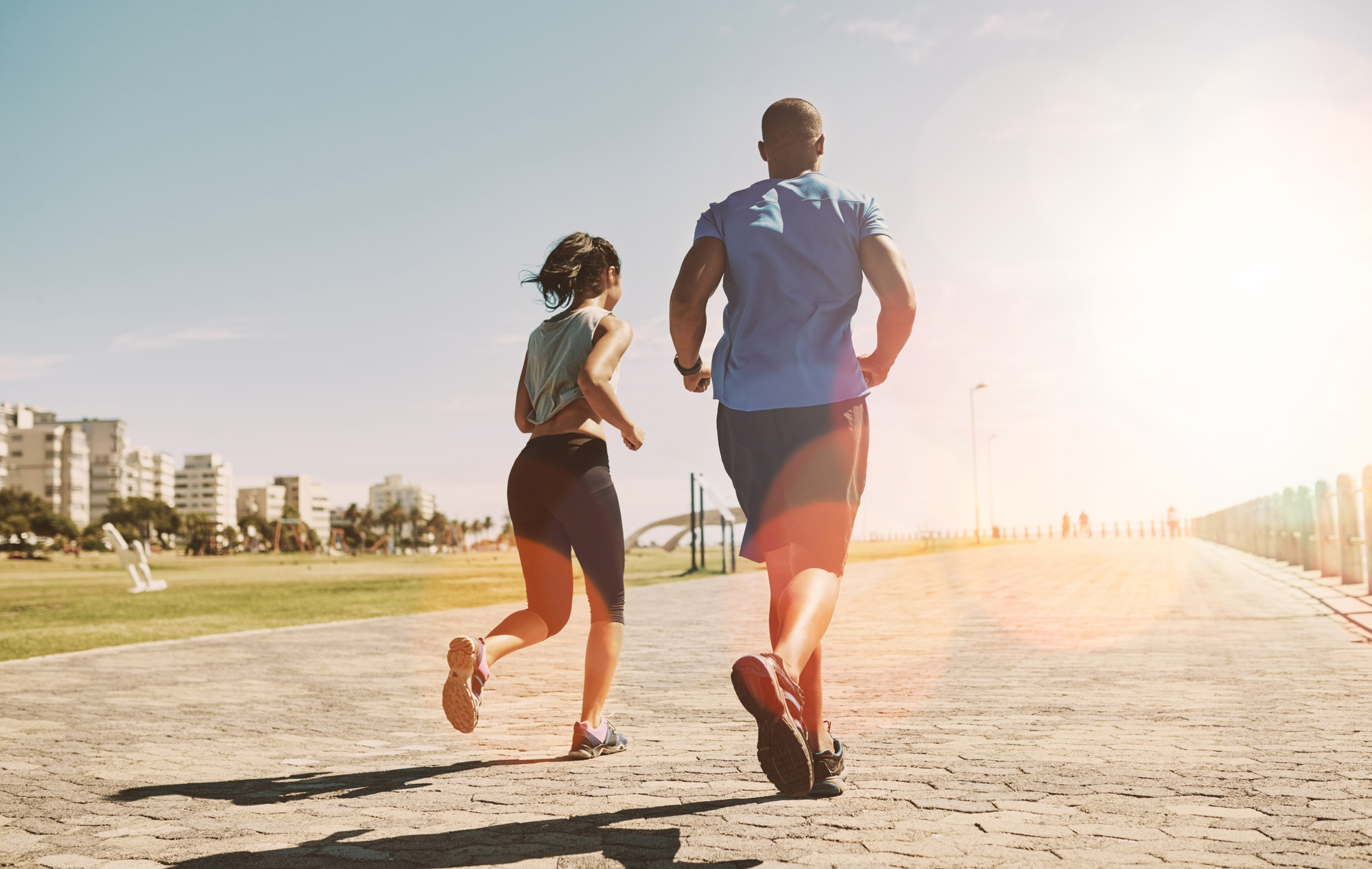 City, running back of couple for fitness, physical health and training for marathon as team. Flare, man and woman with resilience for exercise session, cardio and wellness with endurance on promenade
